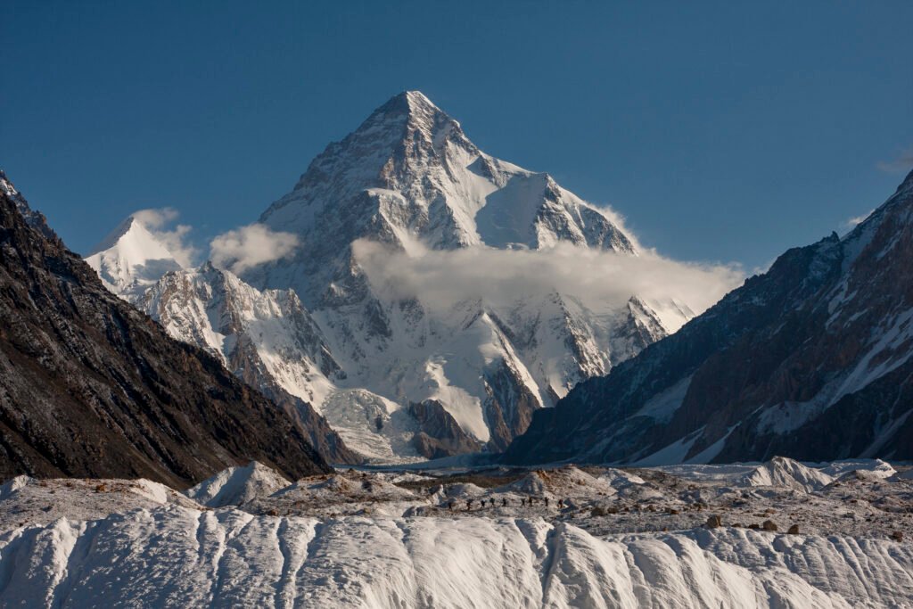 "A group of trekkers approaching K2 Base Camp, with the majestic K2 peak in the background."